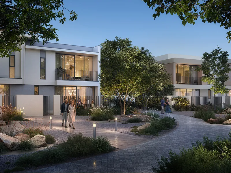 Render of a landscaped pedestrian walkway between Vindera townhouses at dusk.