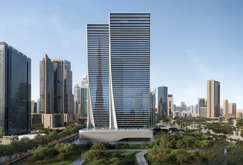 Daytime render of Akala's twin glass towers joined by curved white fins above a podium, with parkland in front and the DIFC and Downtown skyline around them