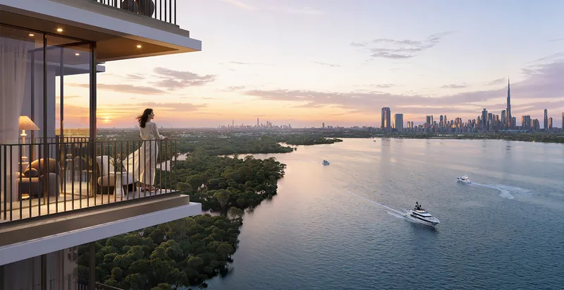 Render of a Creek Haven balcony overlooking Dubai Creek, mangroves and the city skyline at sunset
