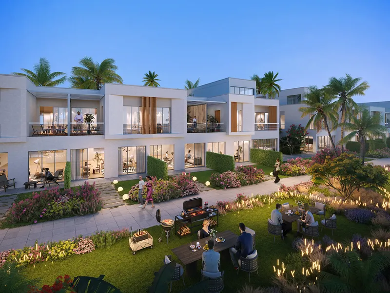 DAMAC Riverside townhouses with balconies behind a landscaped garden where residents are having a barbecue