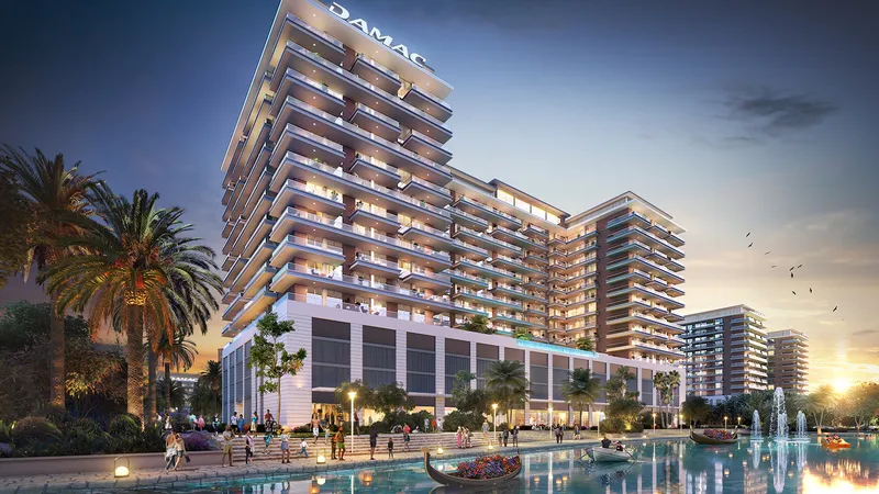DAMAC Riverside Views apartment building at dusk beside a pool and palm trees