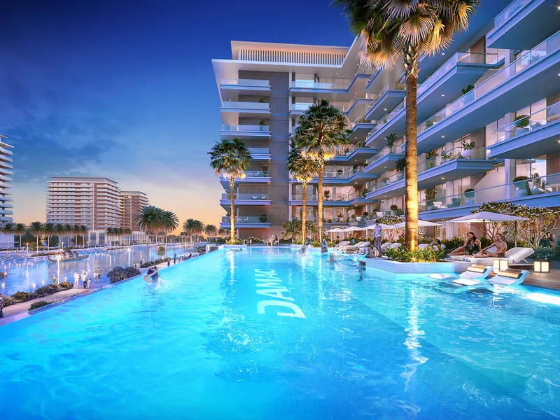 Pool with palm trees at the foot of a DAMAC Riverside Views apartment building