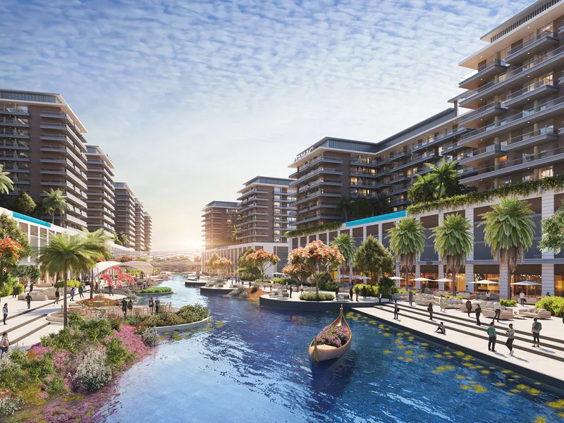 DAMAC Riverside Views apartment buildings lining a river with a landscaped promenade and a small boat