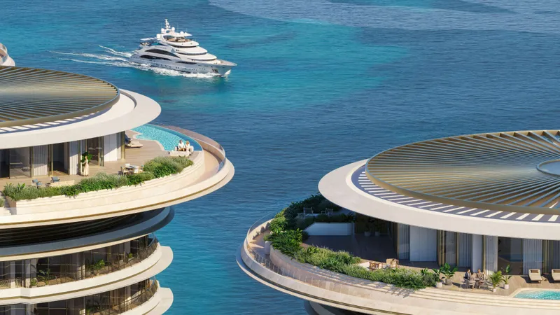 Render of the rounded rooftops and planted terraces of two Dubai Beach EDITION residence towers, with a yacht at sea behind