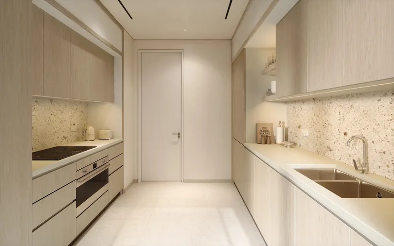 Galley kitchen of an Eden House The Park apartment with pale timber units and terrazzo splashback