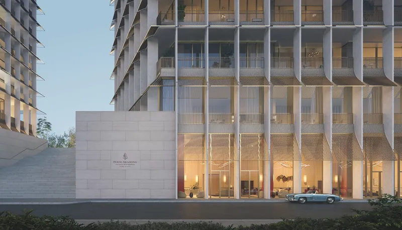 Render of the arrival court at Four Seasons Private Residences Dubai at DIFC, with the tower's slatted facade above a stone entrance wall