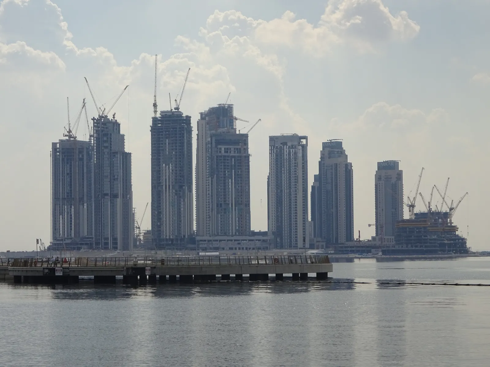 Residential towers under construction with cranes on the Dubai Creek waterfront