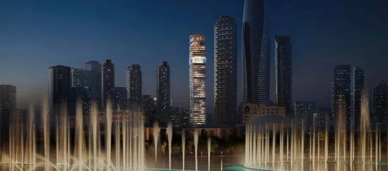 Night render of the lit Inaura Downtown tower with its central orb, seen across the Dubai Fountain in the Downtown skyline