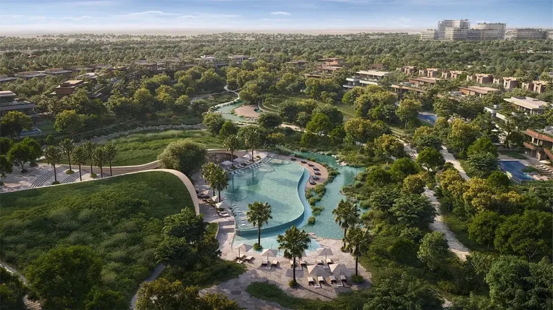Aerial render of The Wilds with a lagoon pool, palm trees and homes set in dense woodland