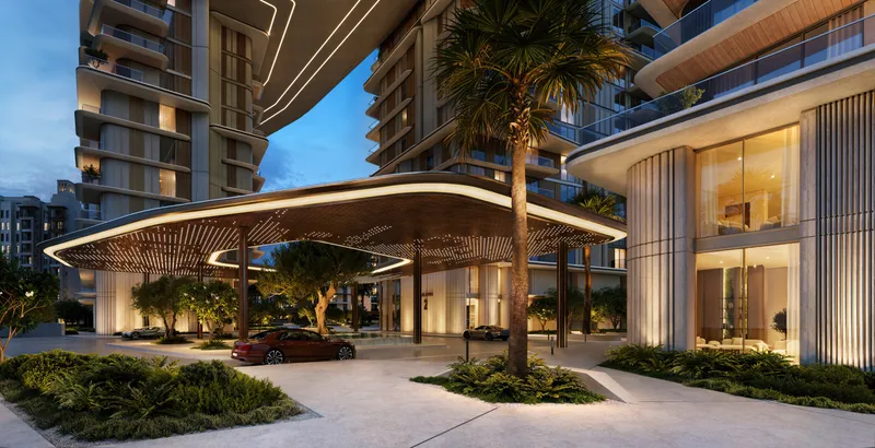 Evening render of the Nourelle drop-off, a lit canopy between the buildings with trees, planting and a car at the entrance