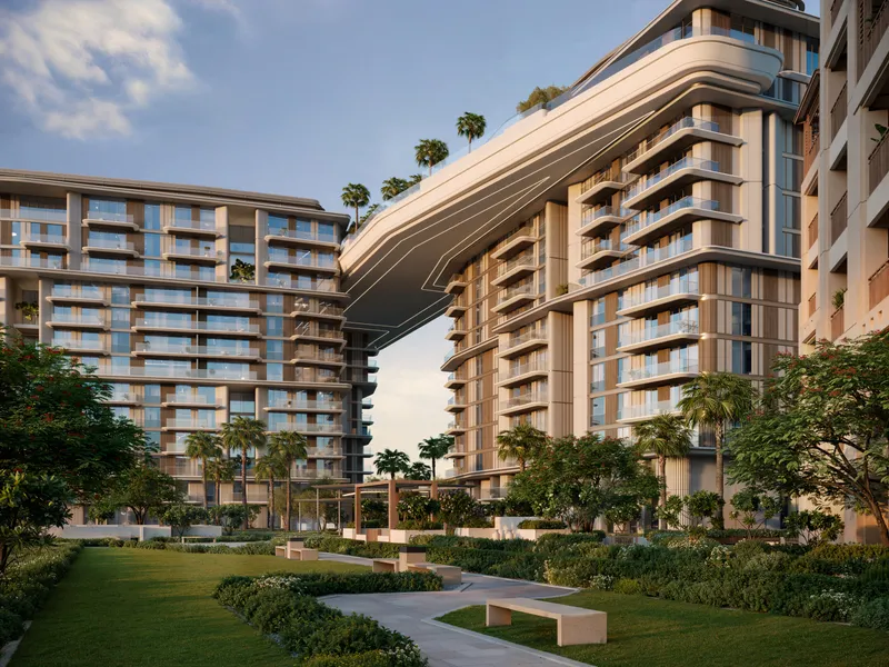 Render of the three Nourelle residential buildings at Madinat Jumeirah Living joined by a curved skybridge above landscaped gardens and lawns