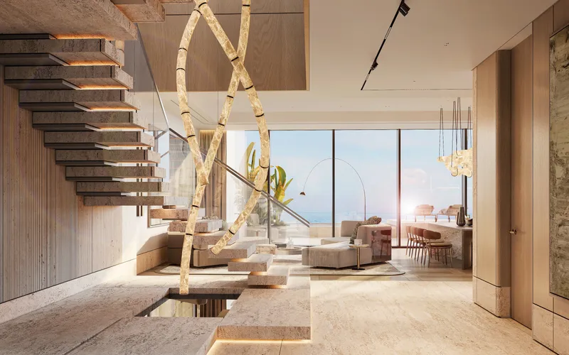 Double-height living room with a sculptural staircase and floor-to-ceiling windows facing the sea