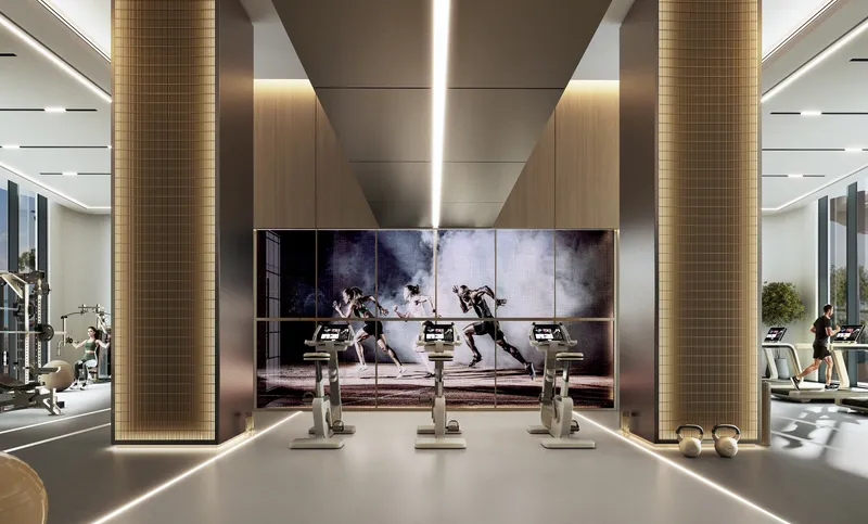 Residents' gym with exercise bikes and a video wall at River Cove Residences