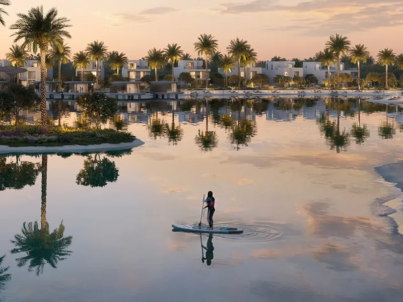 Render of a paddleboarder on the lake at dusk with villas along the shore