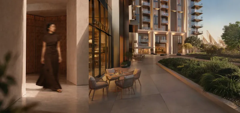 Render of a ground level courtyard at Sei Saadiyat with podium retail and outdoor dining between residential buildings, landscaped planting to one side.