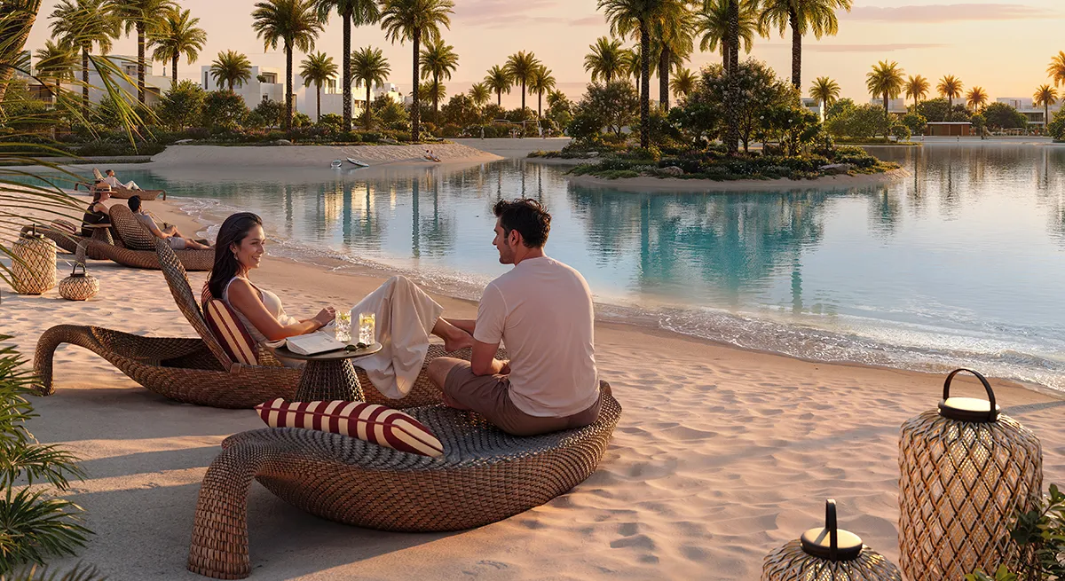 Render of residents relaxing on a sandy lagoon beach with palm trees at sunset