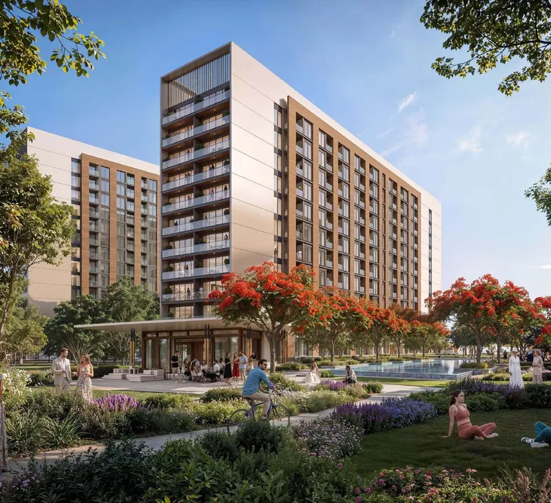 The Woods at Sobha Sanctuary at dusk, an apartment building above a landscaped water feature and flowering trees