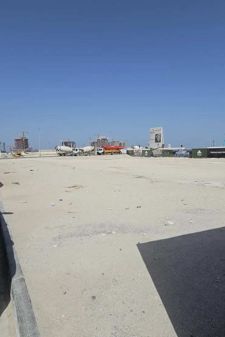 The SOMA Residences plot on Dubai Islands, a cleared sand site with towers under construction behind it