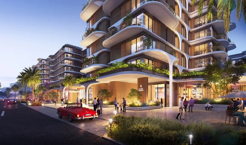 Render of a building entrance at The Beach House at dusk, with curved balconies, planting and a café terrace