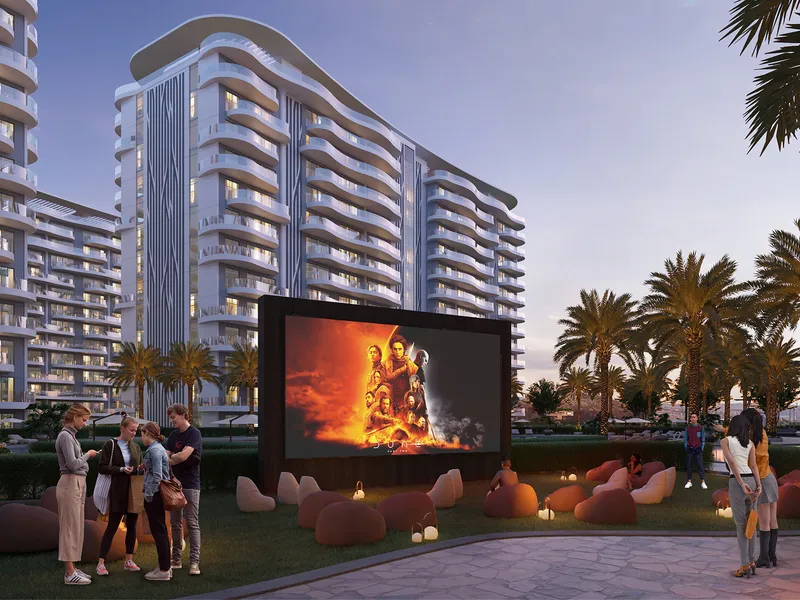 Outdoor cinema screen on a lawn with bean bags in front of the Valencia buildings at dusk