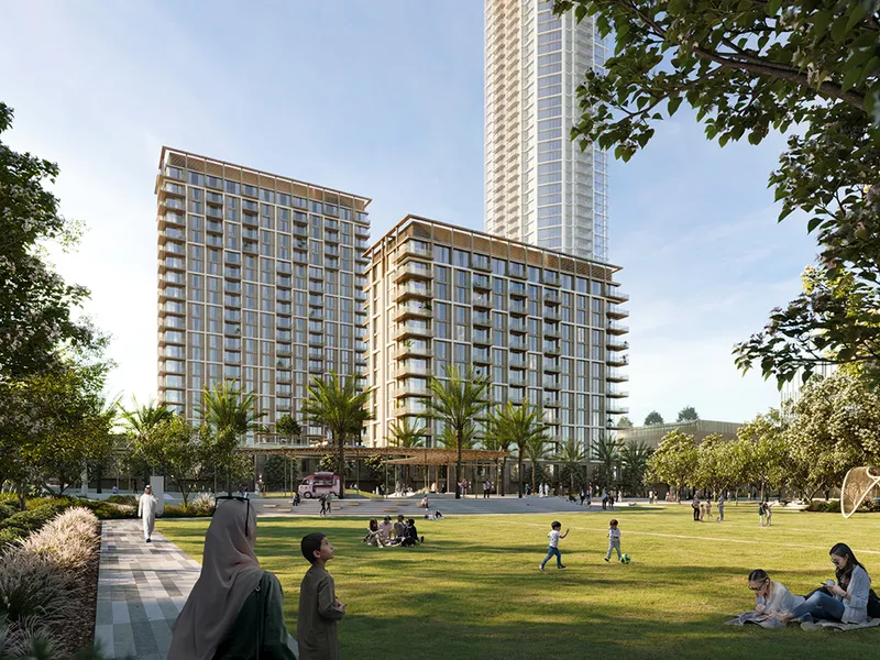 Render of the Aeon buildings by day seen across the park lawn with families