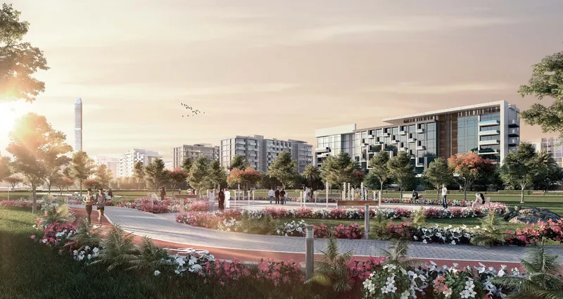 Landscaped park with flower beds and a walking path in front of Azizi Riviera buildings