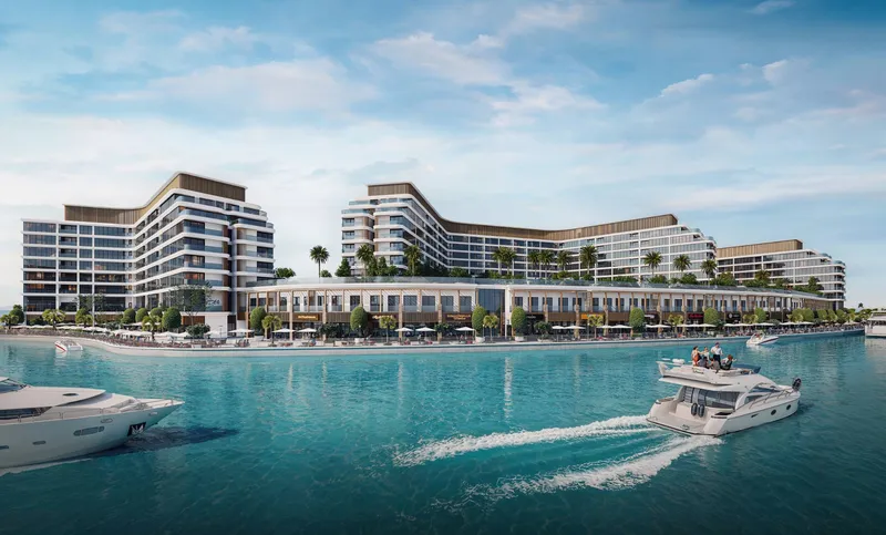 Bayfront Marina Residences above a row of waterfront shops, with boats crossing the marina