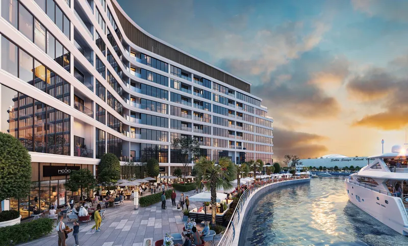 The promenade in front of Bayfront Marina Residences at sunset, with cafés along the water's edge