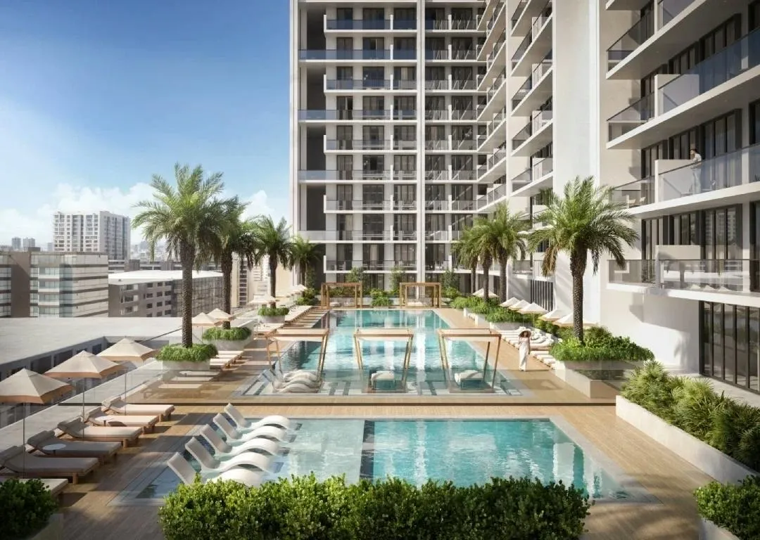 Render of the Binghatti Amberhall pool deck with loungers and palms below the apartment balconies