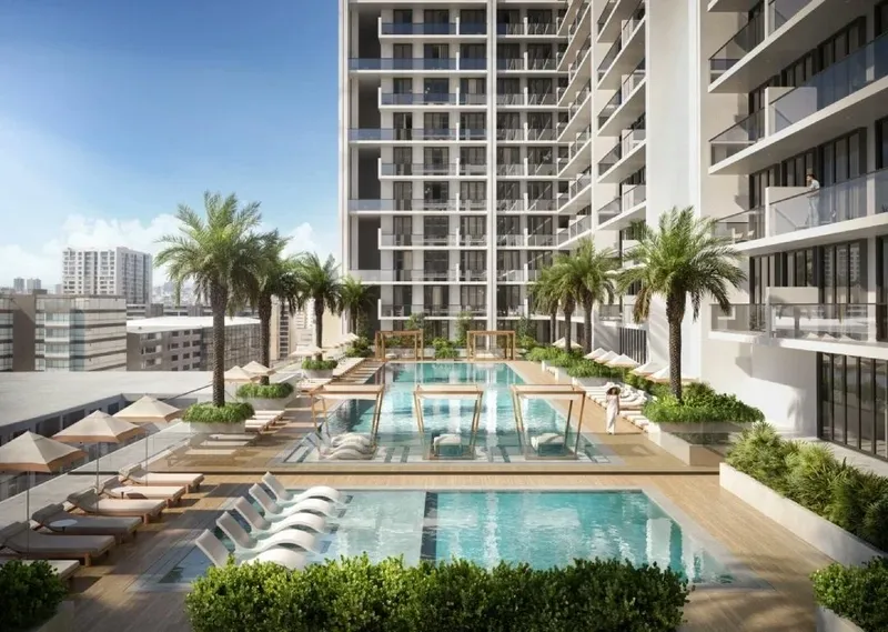 Render of the Binghatti Amberhall pool deck with loungers and palms below the apartment balconies