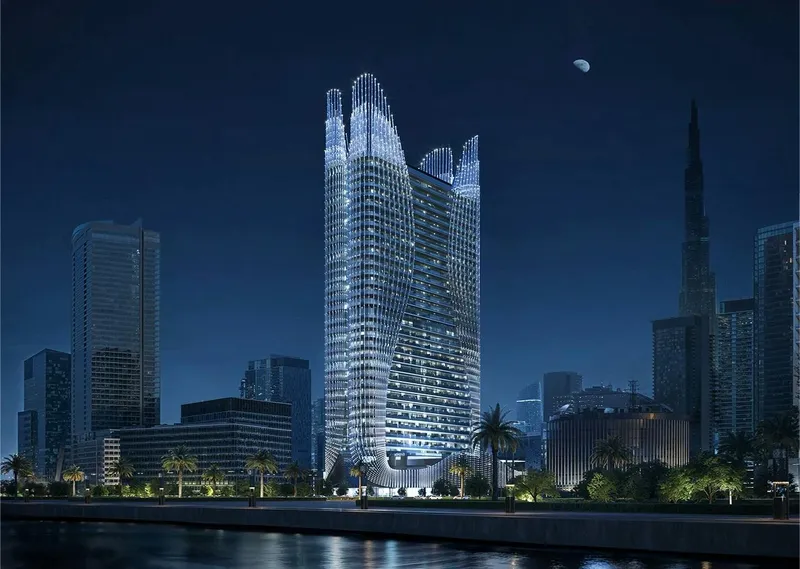 Render of Binghatti Skyhall lit at night beside the water, with its curved crown