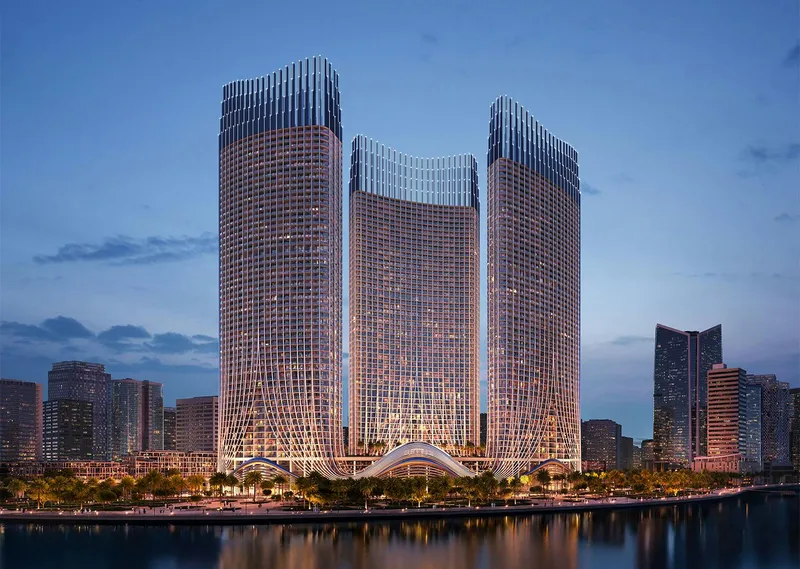 Render of the three Binghatti Skyrise towers at dusk, seen across the water