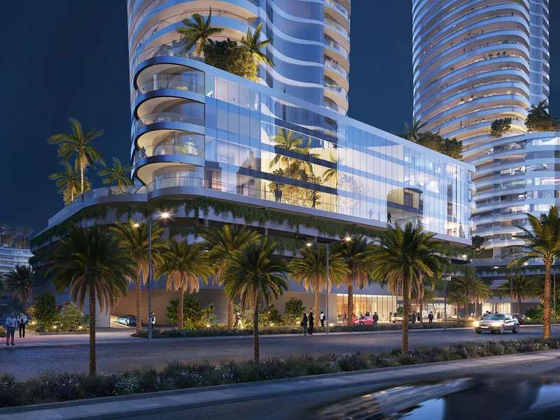 Street-level view of the Canal Crown podium at night, with glazed frontage and palms