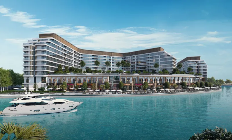 Canalside Marina Residences curving along the canal on Sobha Siniya Island, with a yacht passing in front