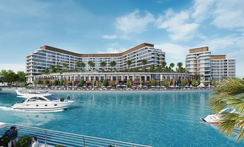 The two buildings of Canalside Marina Residences above a row of waterfront shops, seen across the water