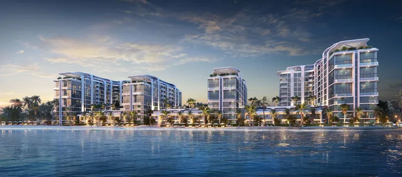 Coastline Beach Residences seen from the water at dusk, with the buildings lit along the shoreline