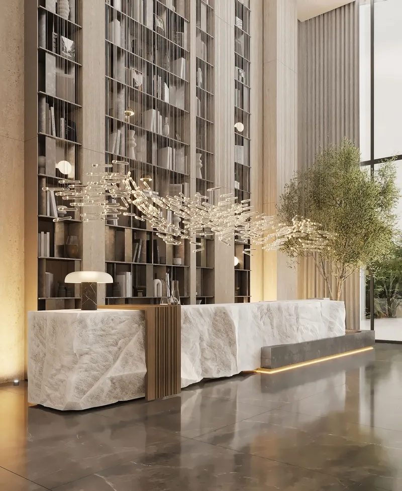 Lobby reception desk in carved stone with a full-height bookshelf wall at Cove by Imtiaz