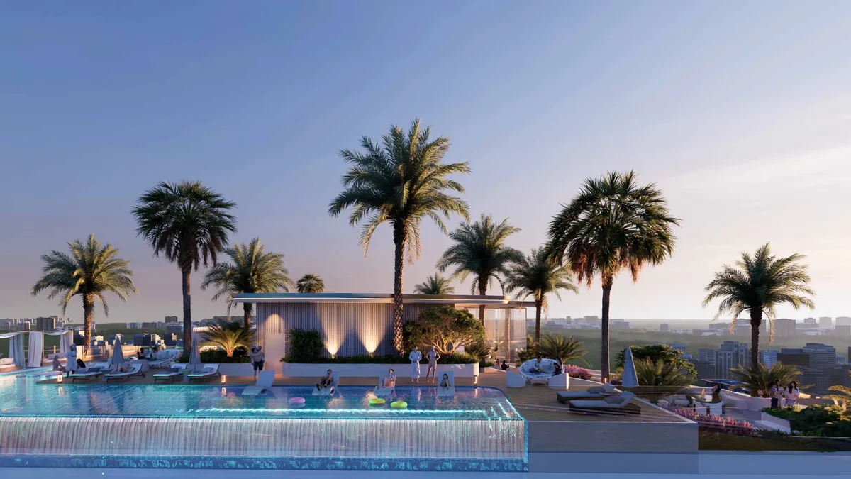 Rooftop infinity pool with palms and sun loungers at Cove Grand by Imtiaz at dusk