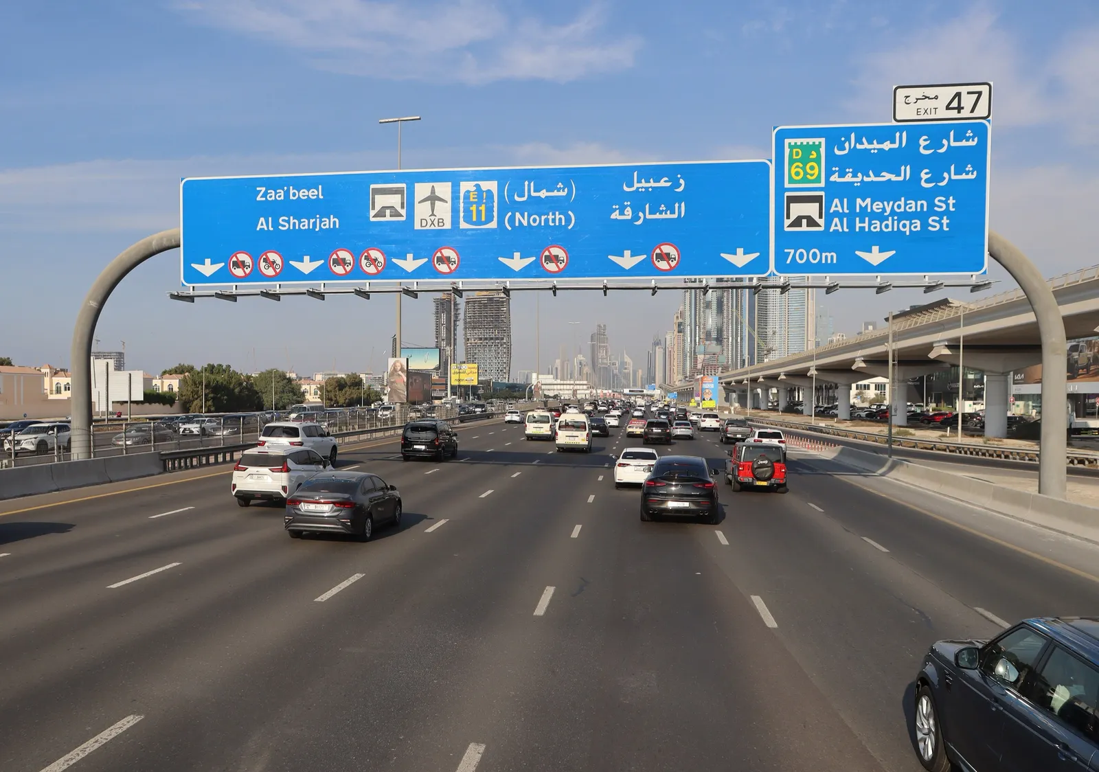 Traffic heading north on Sheikh Zayed Road in Dubai under a sign pointing to Al Sharjah
