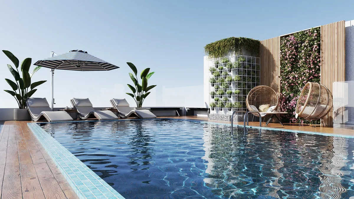 Rooftop swimming pool at Estrella by Nexus with sunbeds, parasols and a green wall