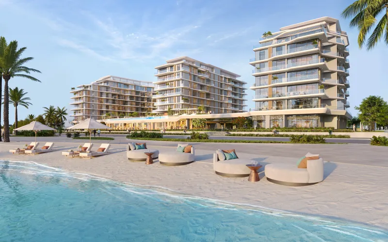 Render of Flora Isle seen from the beach, with loungers and parasols on the sand in front of the buildings