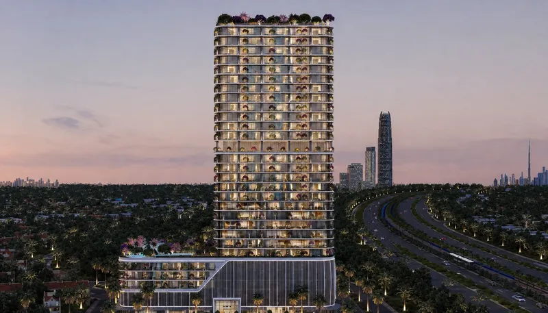 Interstellar Tower at dusk above the low-rise villas of Jumeirah Village Triangle, beside a main road