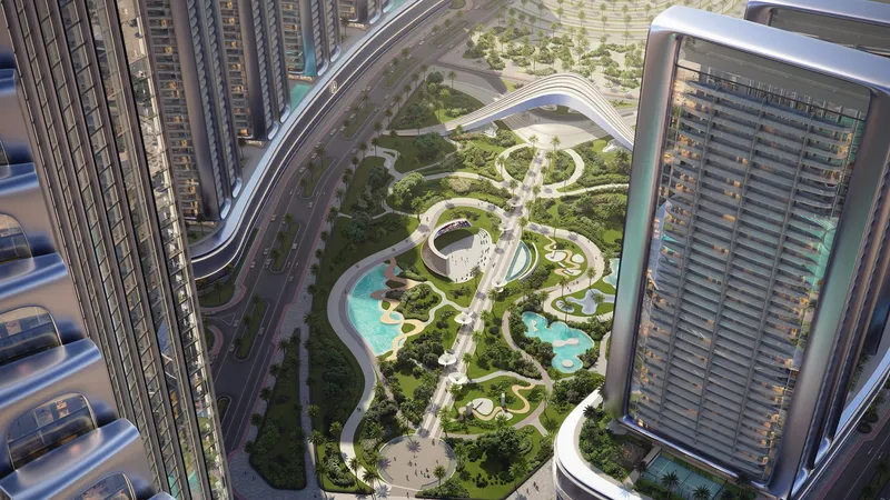 View down between the Binghatti City towers to the Grand Promenade park, with pools, lawns and winding paths