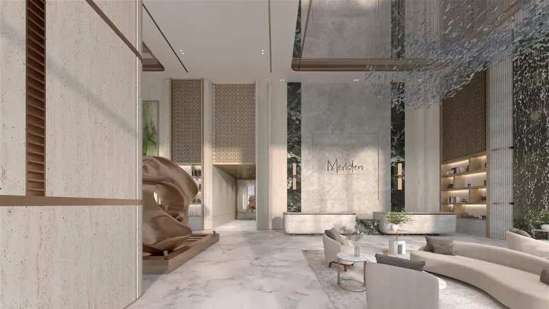 Double-height lobby with stone walls, a sculpture and lounge seating at Meriden Beach Residences