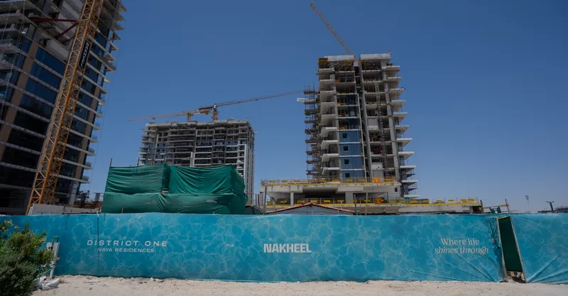 Construction photo of the Naya at District One towers with tower cranes behind the site hoarding