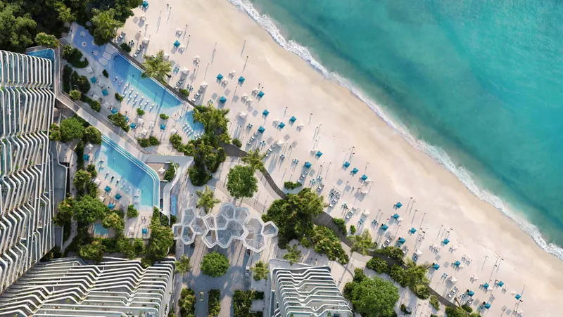 Aerial view of the pools, palm gardens and sunbeds on the beach in front of Nikki Beach Residences