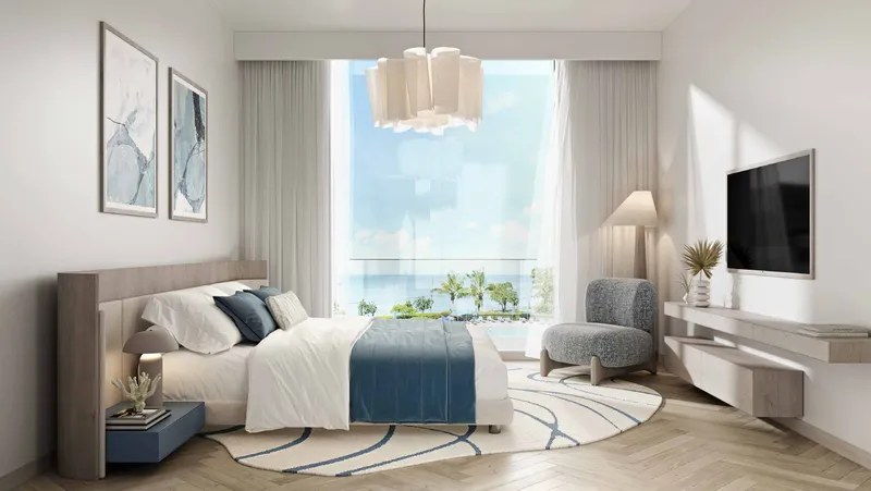 Bedroom in soft neutral tones with a window to the beach at Nikki Beach Residences