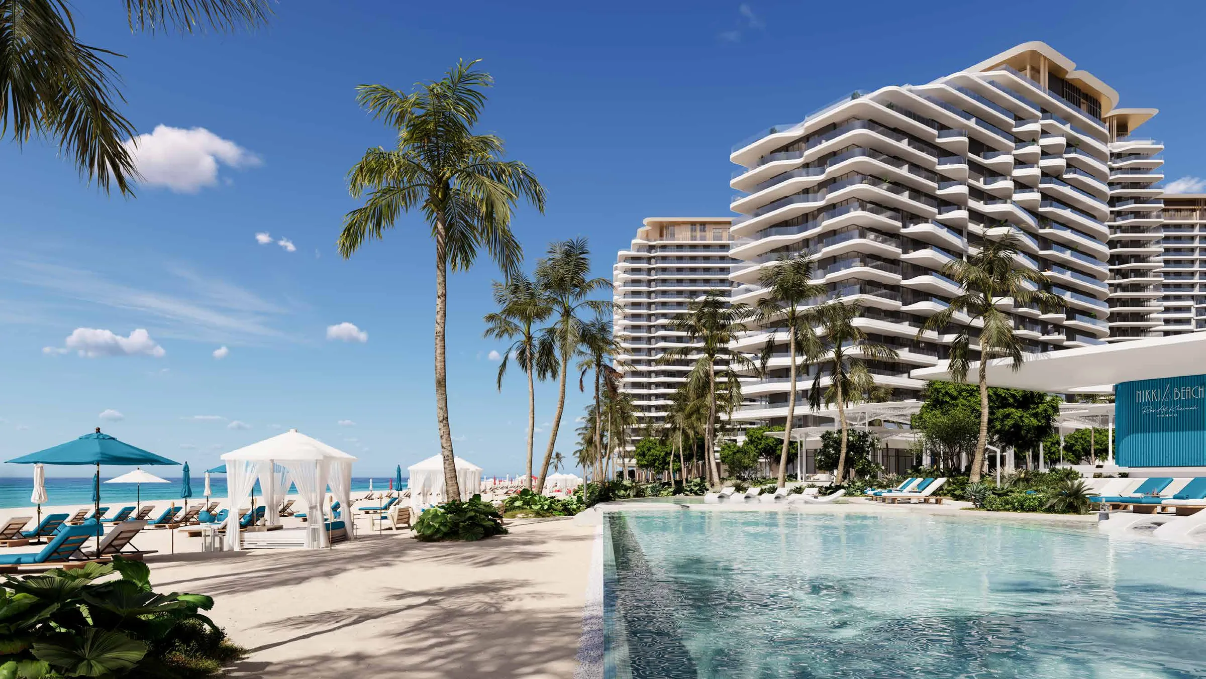 Nikki Beach Residences towers with curved white balconies seen across the beach pool and cabanas