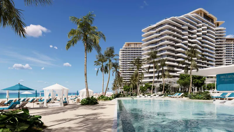 Nikki Beach Residences towers with curved white balconies seen across the beach pool and cabanas