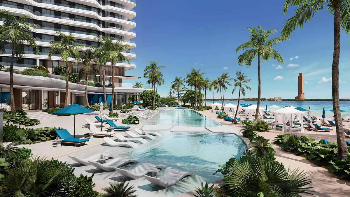Lagoon-style pool with loungers and palm trees beside Nikki Beach Residences